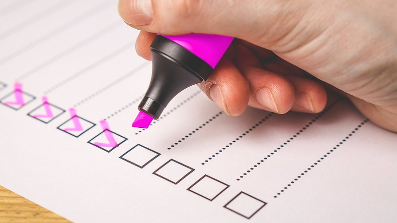 Hand holding pink highlighter above checklist with pink ticks